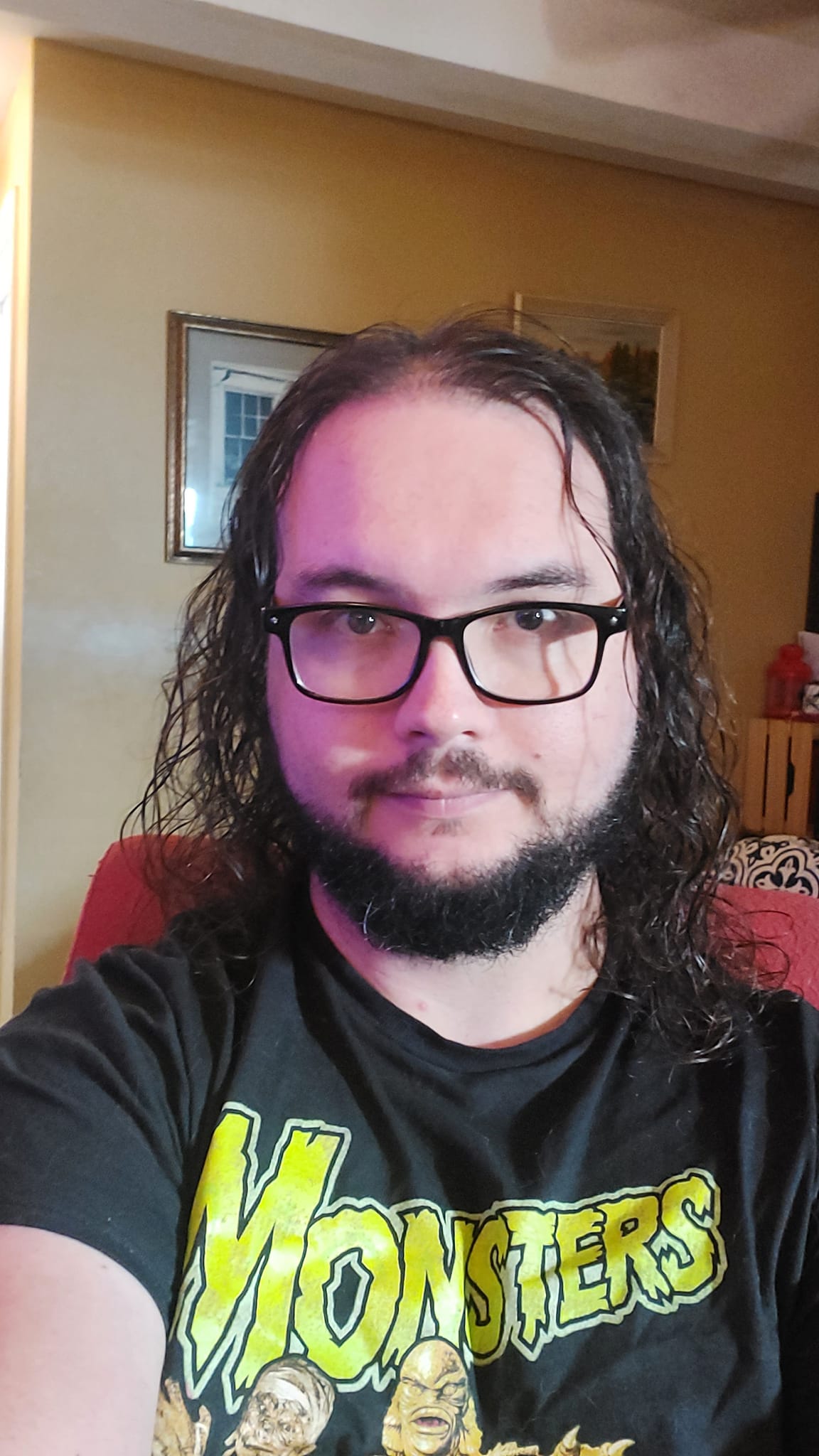 A man with long dark hair and a beard sits in a computer chair, photo 1